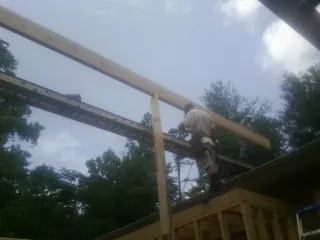 Carpenter setting a ridge beam over a new addition frame — Ice Dam Removal by Roofing Brothers in Manorville