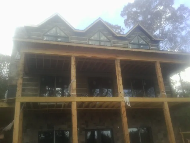Dormers and porch framing on a large log home under construction — Roof Coating work by our crew in Manorville