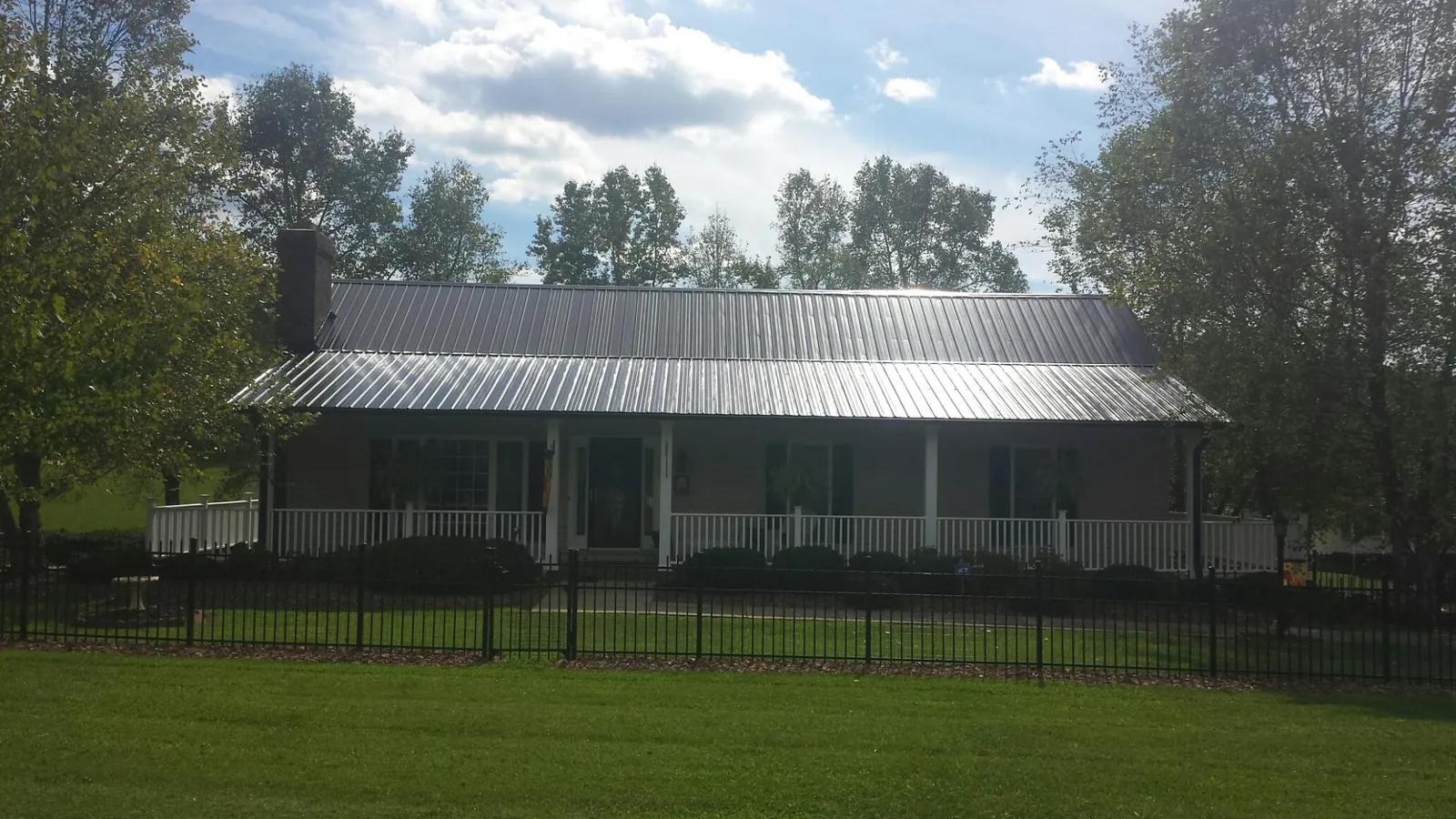 Gray metal roof on a brick ranch with a full width front porch — Gutter Guard Installation work by our crew in Manorville