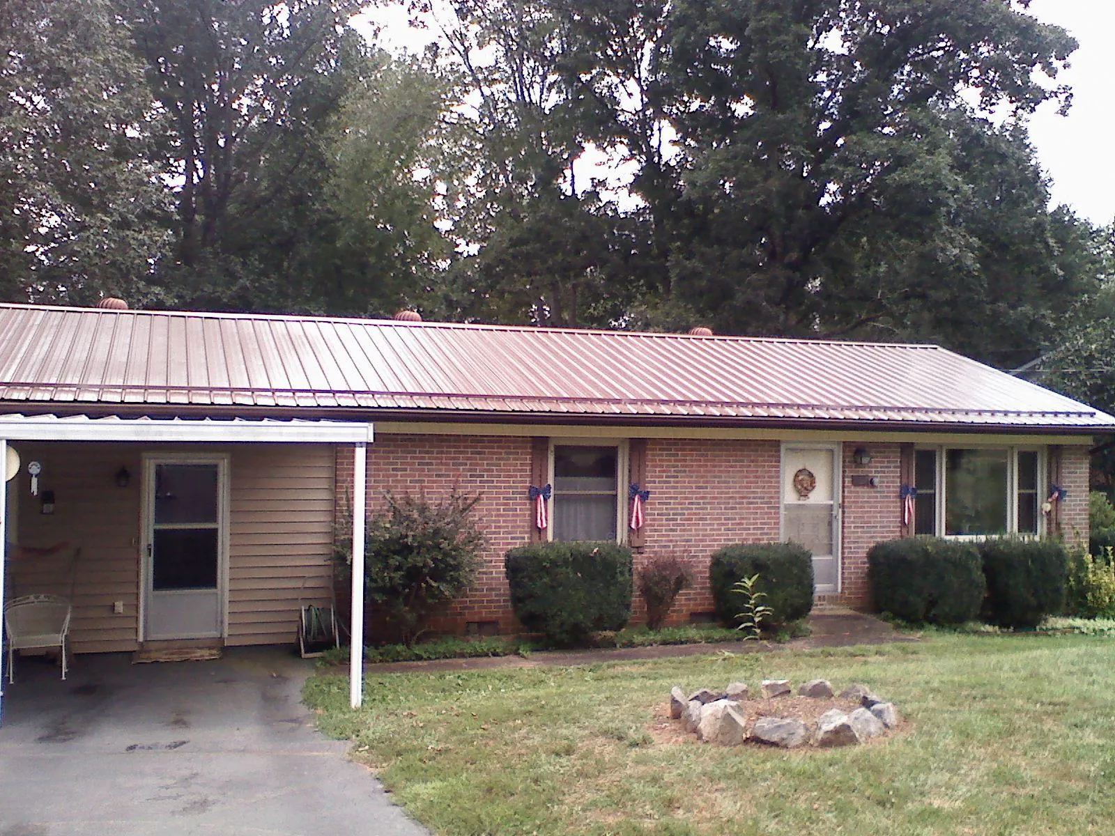 Bronze metal roof and carport on a brick ranch home — Roof Repair work by our crew in Manorville