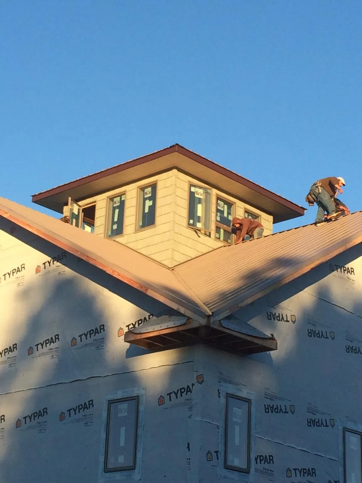 Roofers working around a rooftop cupola on a new metal roof at sunset — Roof Waterproofing in Manorville by Roofing Brothers